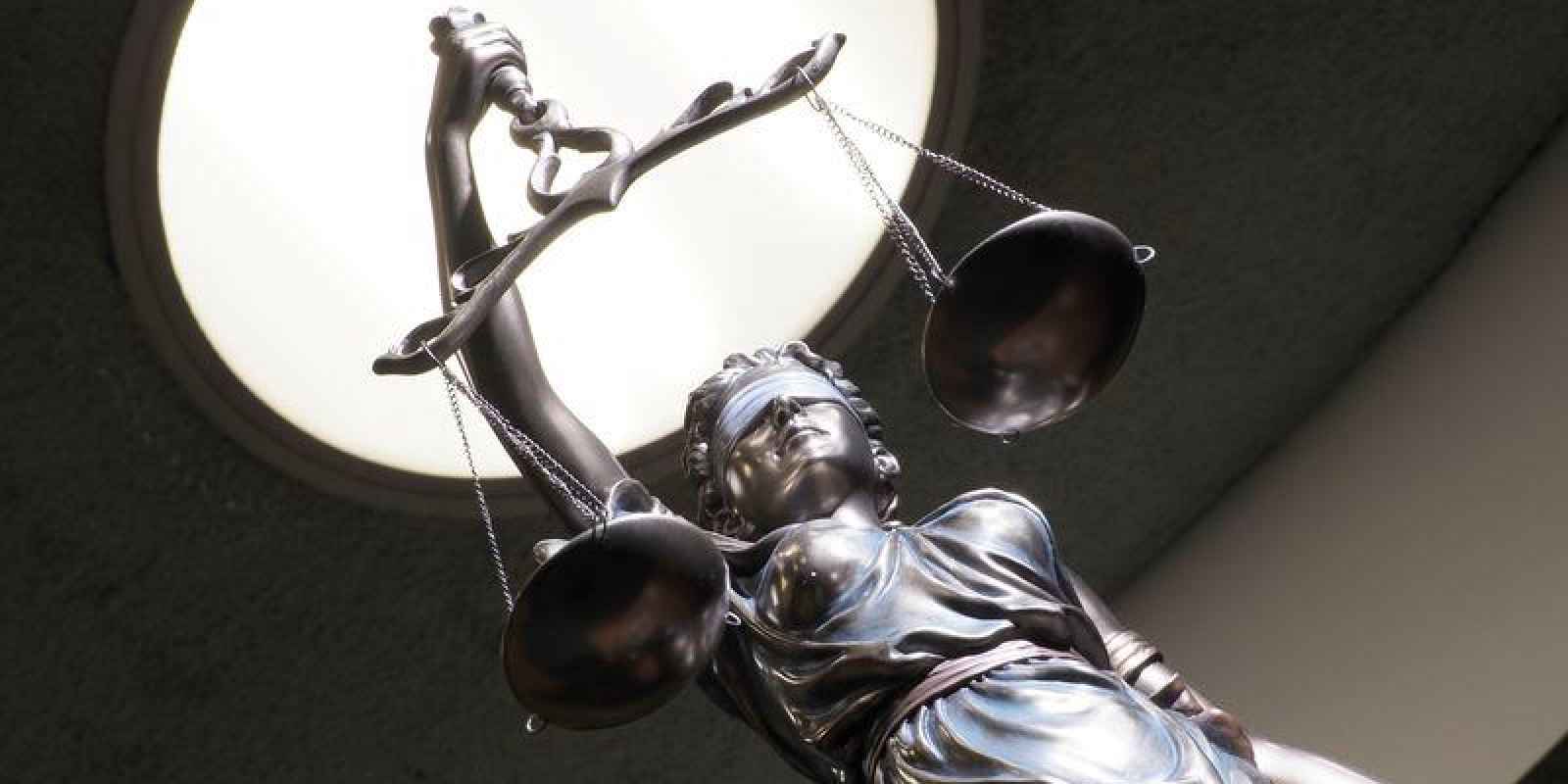 Image of brass statue holding scales in courtroom