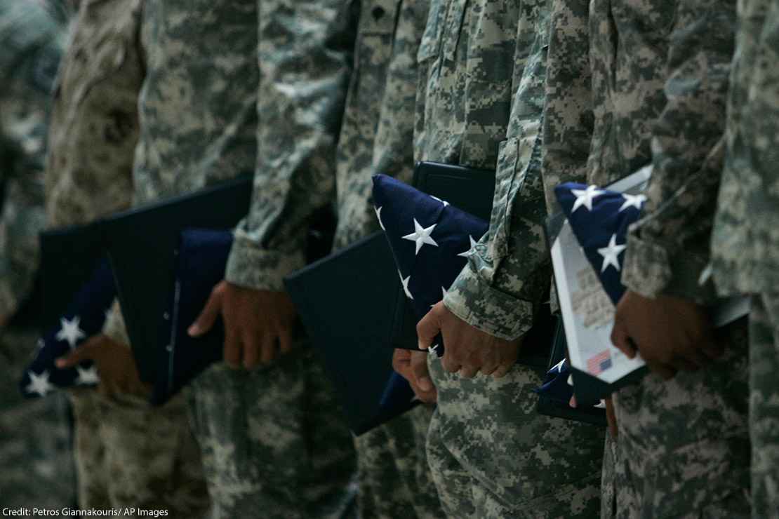 U.S. Army soldiers holding certificates and folded U.S. flags during a ceremony.