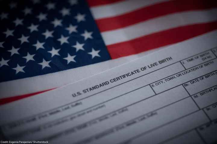 A birth certificate in front of an American flag.