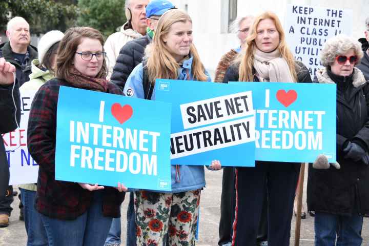 people holding signs that say i (heart) internet freedom and Save Net Neutrality on the capitol steps in Salem