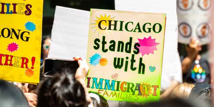 A demonstrator holds a sign that reads "Chicago Stands With Immigrant Families".