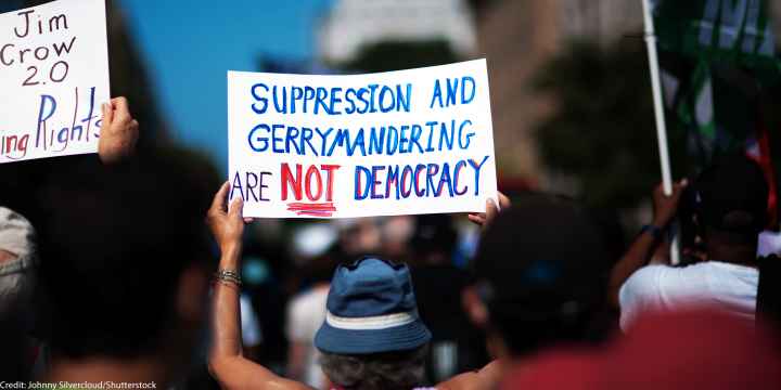 A demonstrator at the March On for Voting Rights in Washington D.C. holds up a sign reading "Suppression and Gerrymandering are Not Democracy".