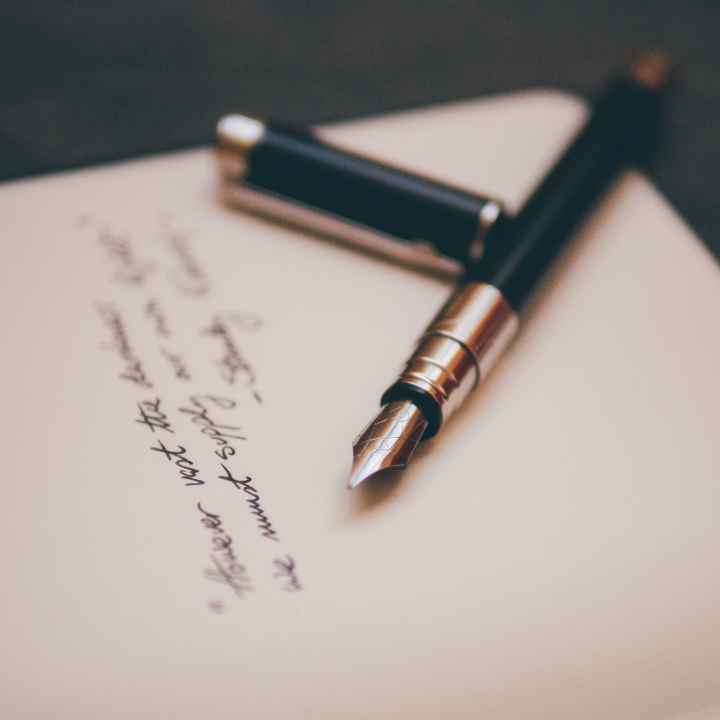 A fountain pen lies on a handwritten note