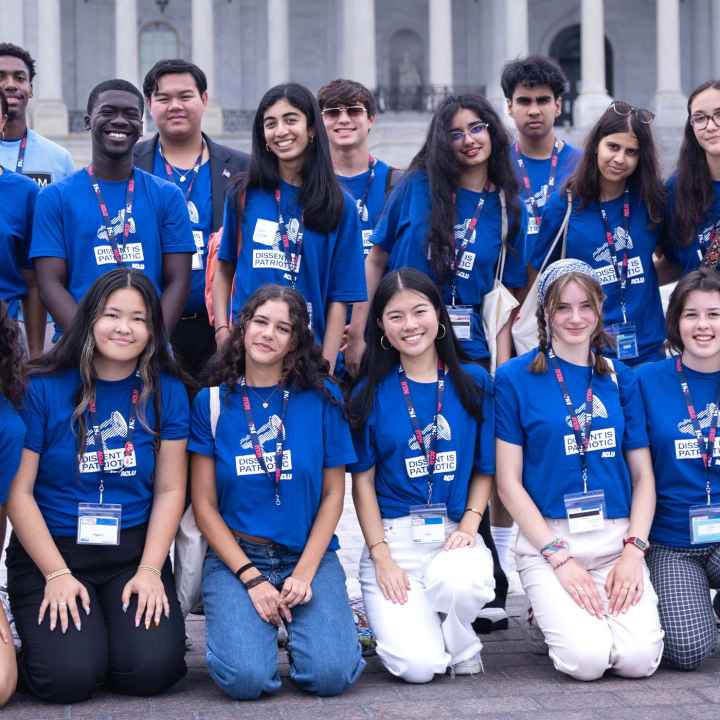 A group of high school students wearing blue shirts reading "DISSENT IS PATRIOTIC" pose for the camera.