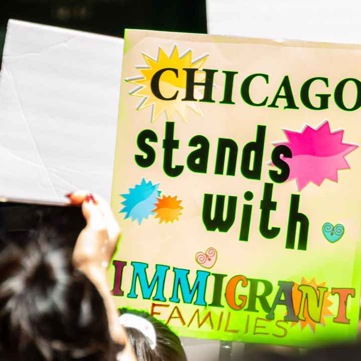 A demonstrator holds a sign that reads "Chicago Stands With Immigrant Families".