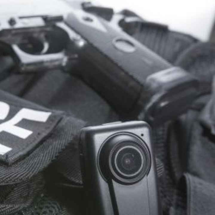 A close-up of sash reading 'Police', along with a body camera and handgun