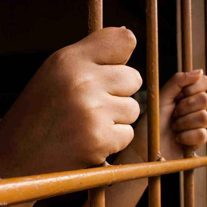 hands grasping jail bars