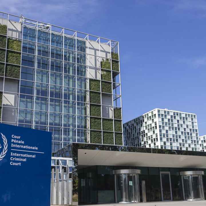 An exterior view of the International Criminal Court In The Hague, Netherlands, with the sign of with of the official logo and inscription of the International Criminal Court in the foreground.